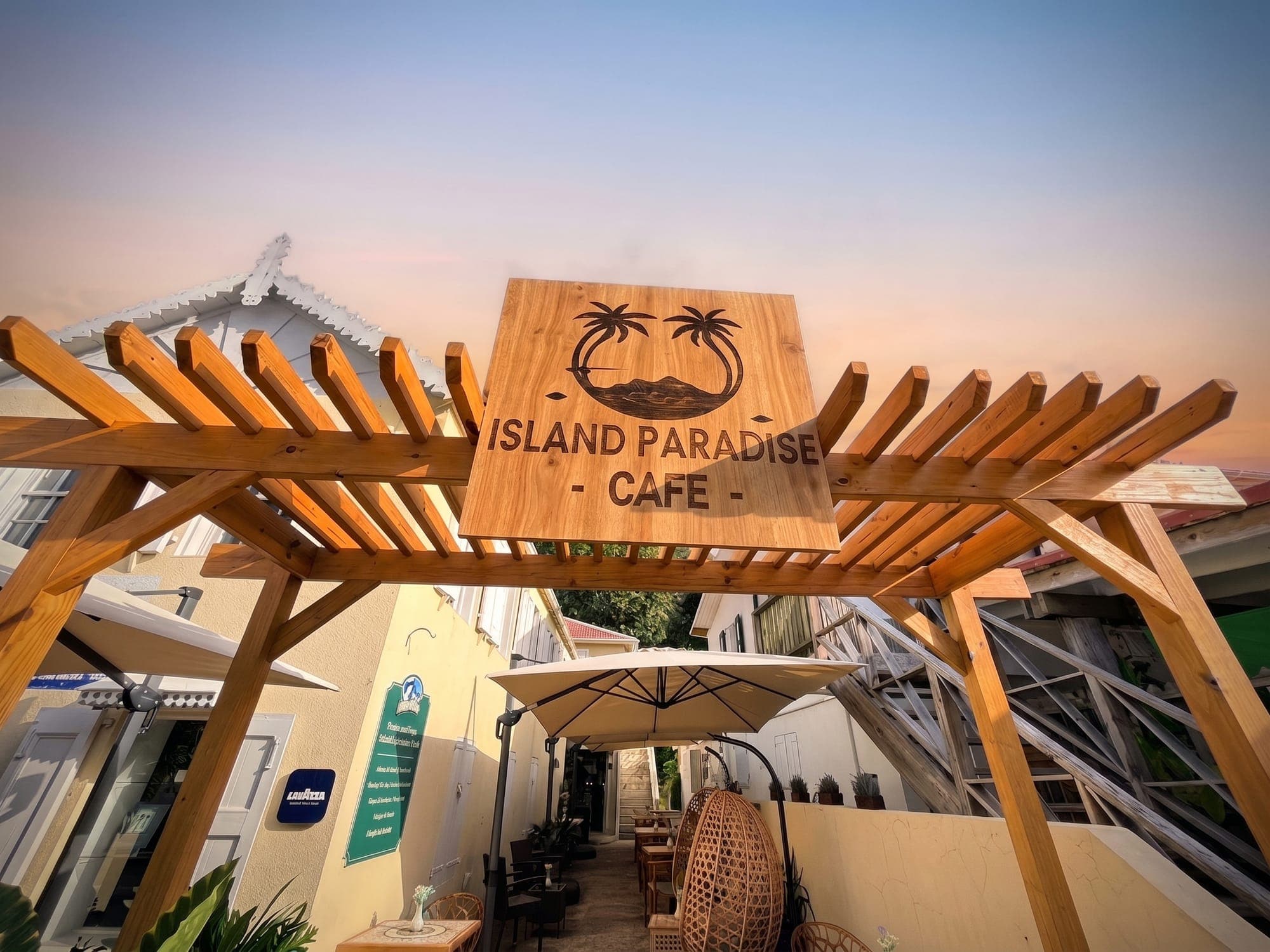 The cafe pergola and its carved sign against the evening sky