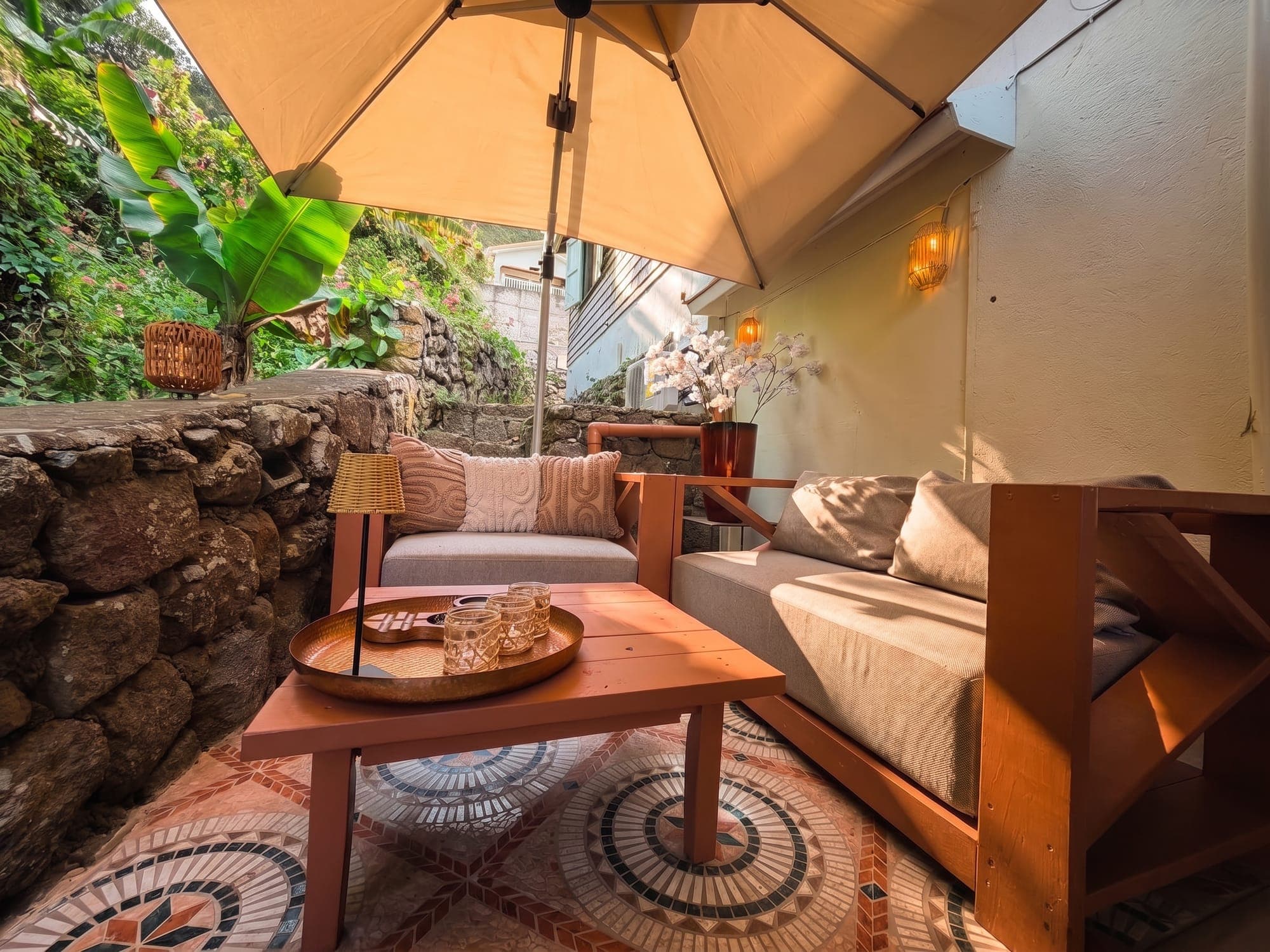 The lounge corner, a sofa under a parasol beside the stone wall